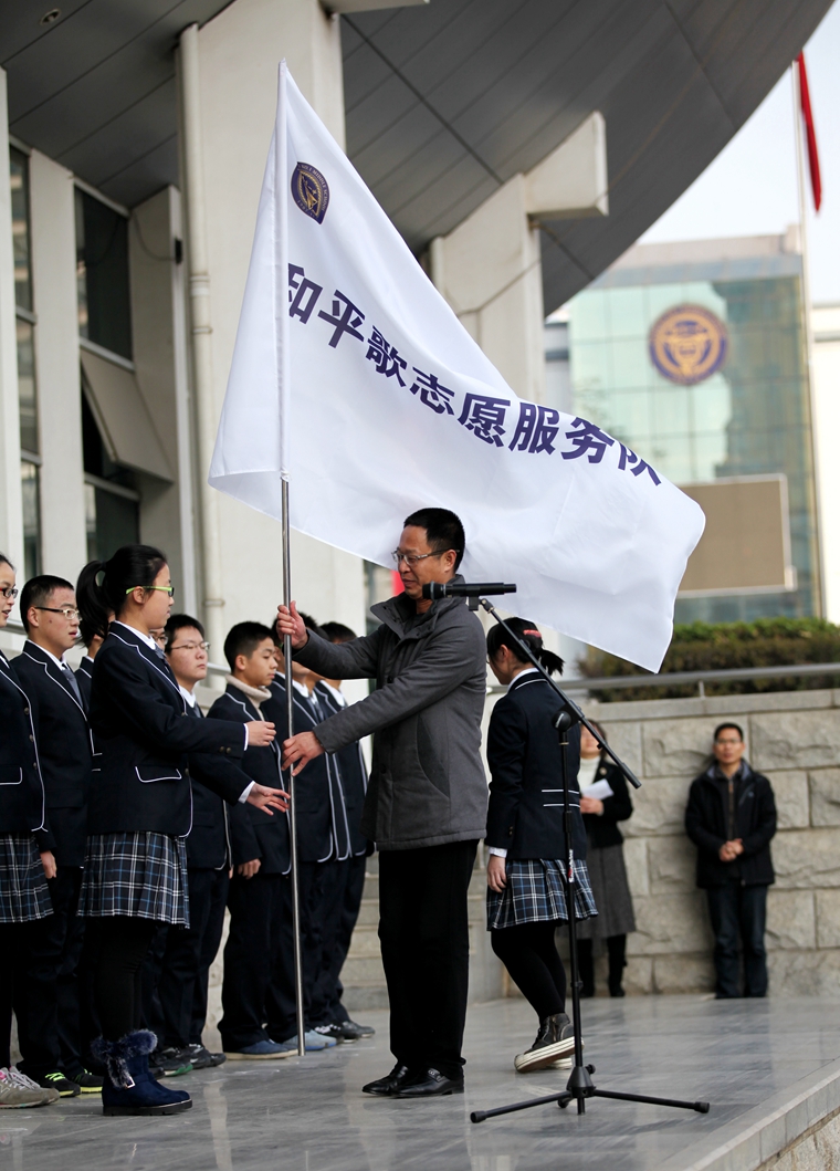 尤小平校长向“和平歌”志愿者服务队队长授旗