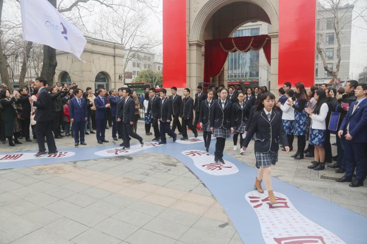 同学们在老师和家长的欢迎下进入成人门，踏上标有”修身、齐家、治国、平天下“的成人”路